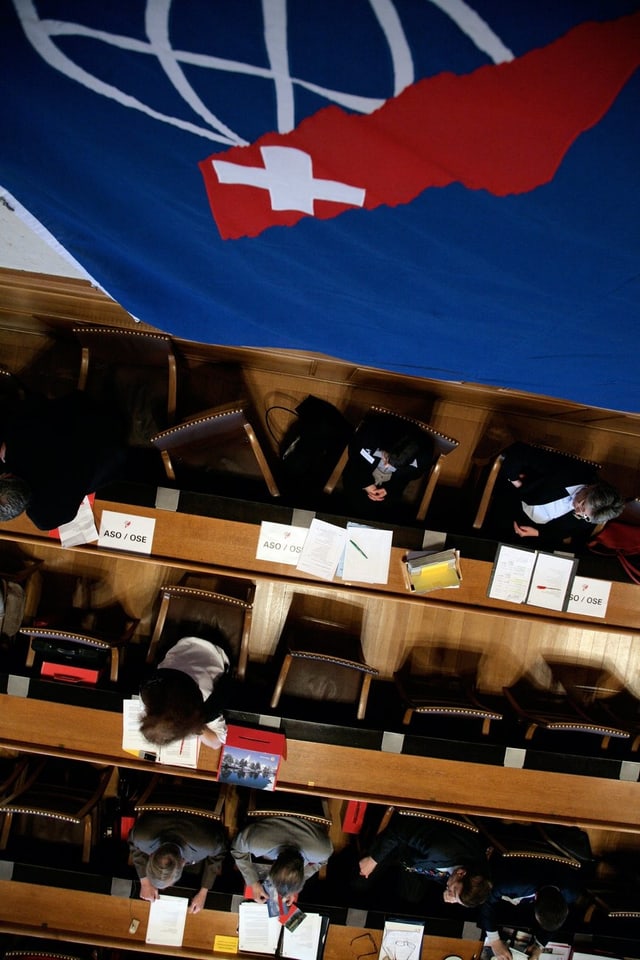 Logo des Auslandschweizerrates vor einem Rat. Logo des Auslandschweizerrates vor einem Rat.