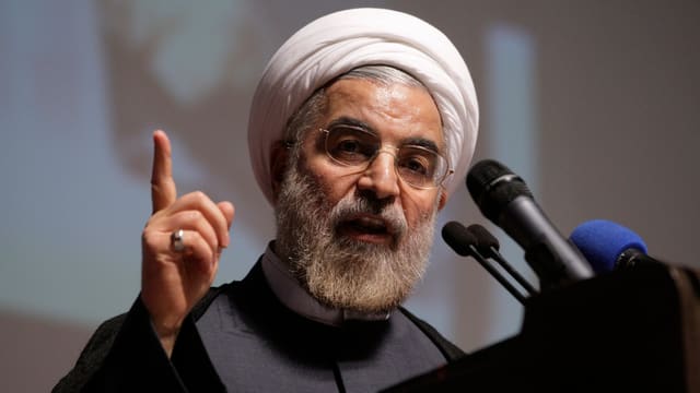 Rohani an einem Rednerpult mit erhobenen Finger. Rohani an einem Rednerpult mit erhobenen Finger.