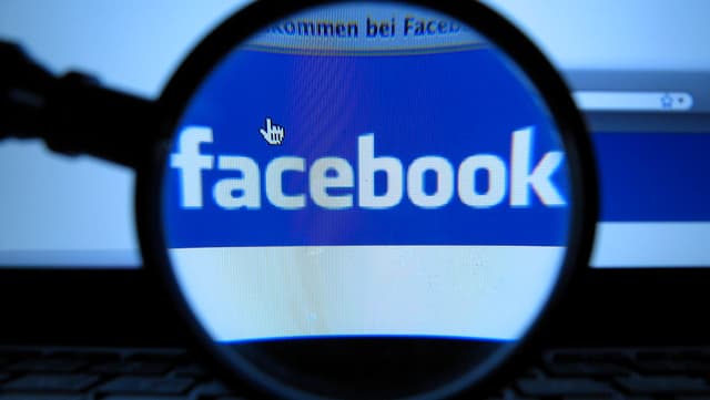 Facebook-Logo unter einer Lupe. Facebook-Logo unter einer Lupe.