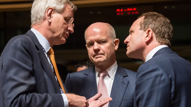 Drei Männer diskutieren miteinander. Drei Männer diskutieren miteinander.