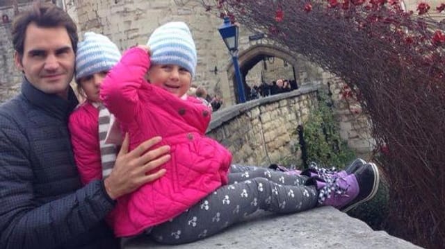 Roger Federer mit den Zwillingsmädchen, die auf einer Mauer sitzen. Roger Federer mit den Zwillingsmädchen, die auf einer Mauer sitzen.