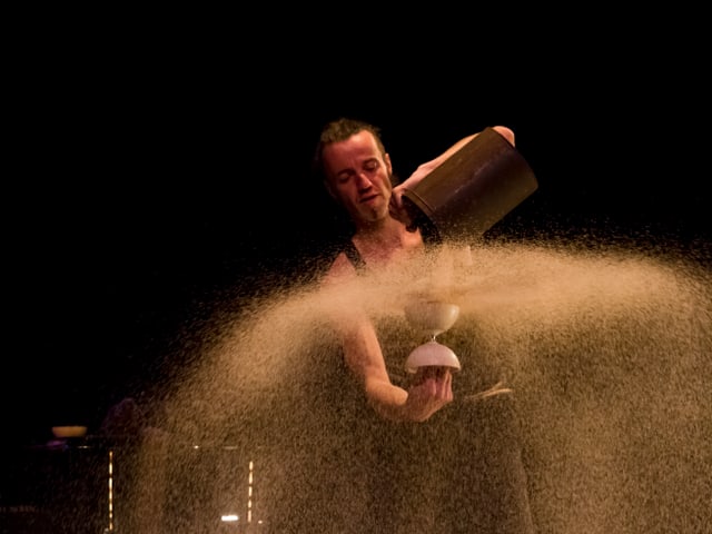 Müller schüttet Sand in ein Diabolo, der wie Wasser verspritzt. 