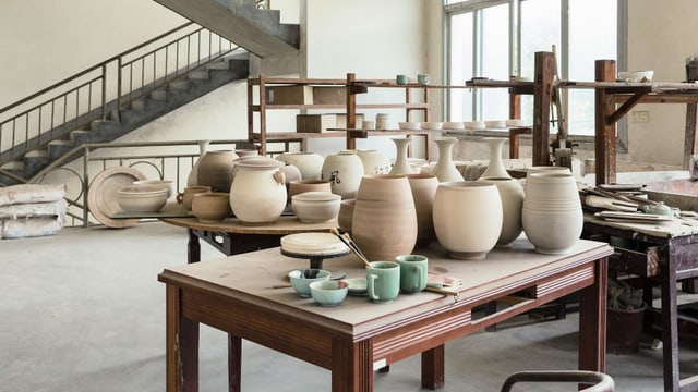 Arbeitsräume der Porzellan-Werkstatt. Viele Schalen, Vasen und Tassen auf einem Tisch. Arbeitsräume der Porzellan-Werkstatt. Viele Schalen, Vasen und Tassen auf einem Tisch.