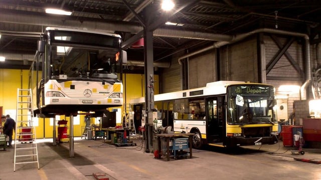 Zwei Busse mit unterschiedlichen Beschriftungen in einem Depot Zwei Busse mit unterschiedlichen Beschriftungen in einem Depot