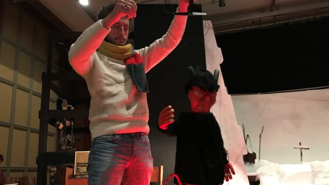Ein Mann hält eine Teufelsmarionette in den Händen. Ein Mann hält eine Teufelsmarionette in den Händen.