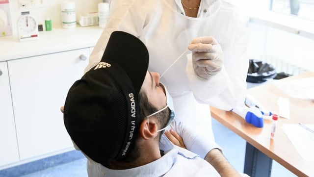 Ärztin nimmt bei Patient Abstrich in der Nase.