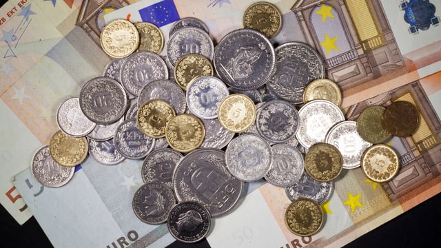 Schweizer-Franken-Münzen liegen auf Euro-Münzen. Schweizer-Franken-Münzen liegen auf Euro-Münzen.