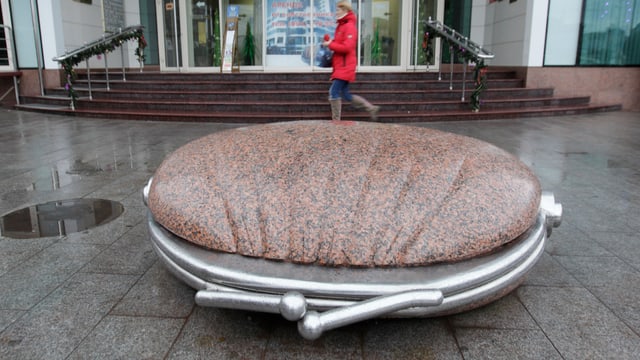 Eine Person geht an einer Skulptur, die an ein Portemonnaie erinnert, vorbei Eine Person geht an einer Skulptur, die an ein Portemonnaie erinnert, vorbei