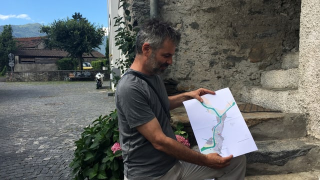 Ein Mann mit Bart schaut auf eine auf den Knien ausgebreitete Karte. Ein Mann mit Bart schaut auf eine auf den Knien ausgebreitete Karte.