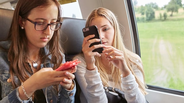 Zwei Mädchen im Zug mit Smartphones Zwei Mädchen im Zug mit Smartphones
