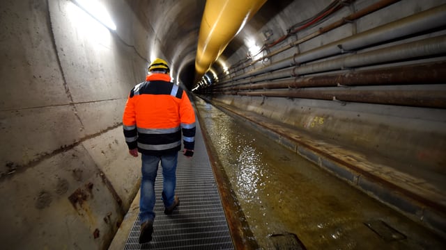 Mann in oranger Weste zu Fuss in einem Tunnel. Mann in oranger Weste zu Fuss in einem Tunnel.