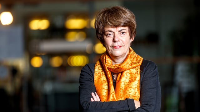 Eine Frau mit verschränkten Armen und buntem Schal. Eine Frau mit verschränkten Armen und buntem Schal.