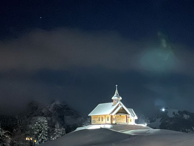 Die beleuchtete Kapelle auf dem Stoos im Dunkeln.