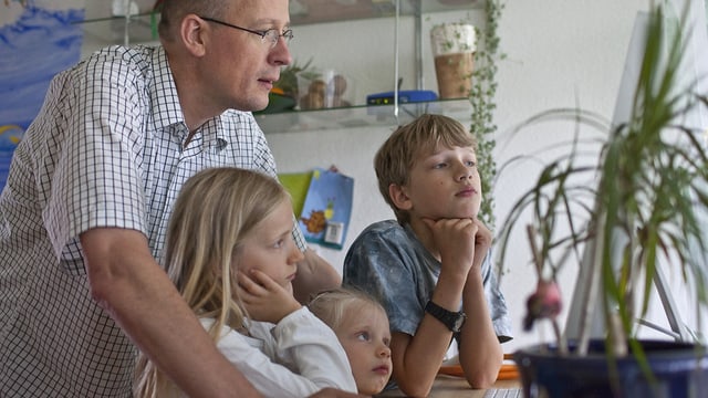Vater sitzt mit drei Kindern vor Computer. Symbolbild für den Erfolg von Familienunternehmen. Vater sitzt mit drei Kindern vor Computer. Symbolbild für den Erfolg von Familienunternehmen.