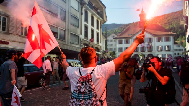 Ein Mann mit Feuerwerk in der einen und einer Jura-Fahne in der anderen Hand. Ein Mann mit Feuerwerk in der einen und einer Jura-Fahne in der anderen Hand.