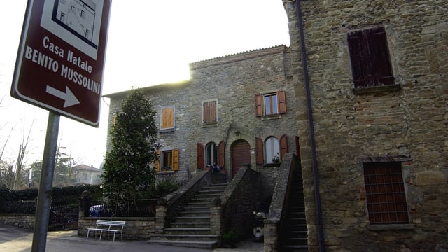 Schild mit der Aufschrift «Casa Natale Benito Mussolini» weist auf ein Haus hin. Schild mit der Aufschrift «Casa Natale Benito Mussolini» weist auf ein Haus hin.