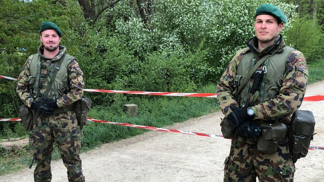 Zwei Soldaten im Tarnanzug vor einem Absperrband. Zwei Soldaten im Tarnanzug vor einem Absperrband.