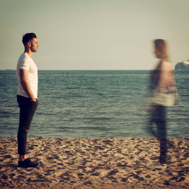 Ein Paar steht am Strand. Die Frau verschwimmt. Ein Paar steht am Strand. Die Frau verschwimmt.