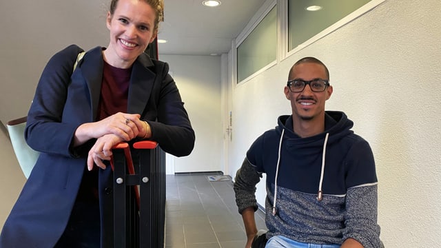 eine Frau steht neben einem Mann im Rollstuhl eine Frau steht neben einem Mann im Rollstuhl