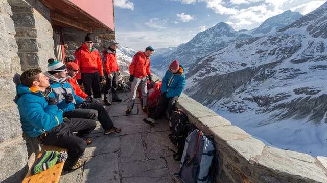 Menschen an einer Hütte vor einem Bergpanorama Menschen an einer Hütte vor einem Bergpanorama
