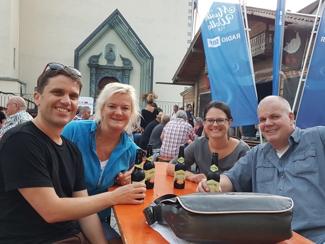 Vier fröhliche Männer und Frauen an einem Tisch.