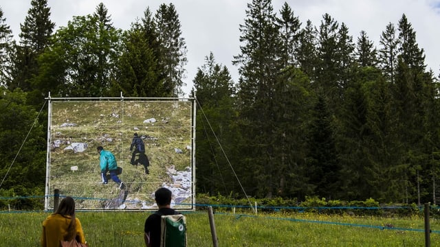 Zwei Menschen betrachten eine Fotografie, auf der zwei Menschen in der Natur zu erkennen sind. Zwei Menschen betrachten eine Fotografie, auf der zwei Menschen in der Natur zu erkennen sind.
