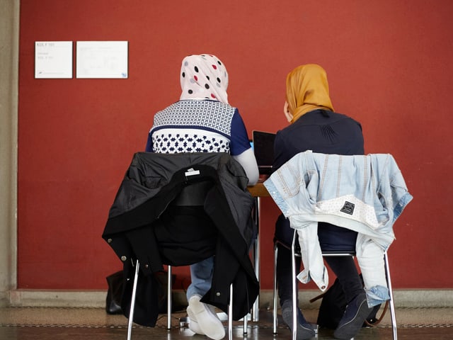 Zwei Frauen mit Kopftuch an einem Pult. Man sieht sie von hinten. Zwei Frauen mit Kopftuch an einem Pult. Man sieht sie von hinten.