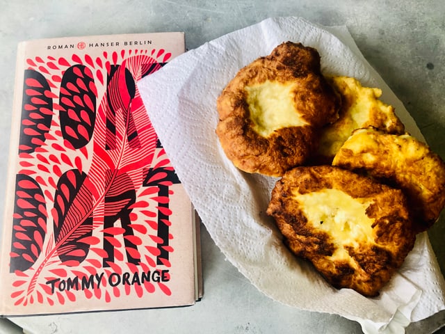 Neben dem Roman «Dort Dort» von Tommy Orange steht ein Teller mit selbstgemachtem Fry Bread. Neben dem Roman «Dort Dort» von Tommy Orange steht ein Teller mit selbstgemachtem Fry Bread.