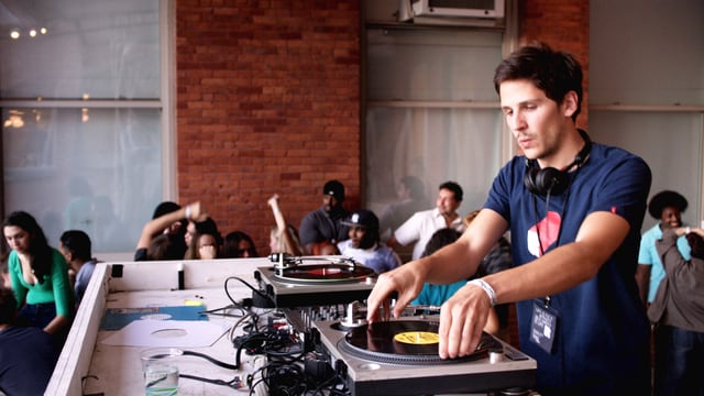 Ein Dj legt auf. Im Hintergrund sind Menschen. Ein Dj legt auf. Im Hintergrund sind Menschen.
