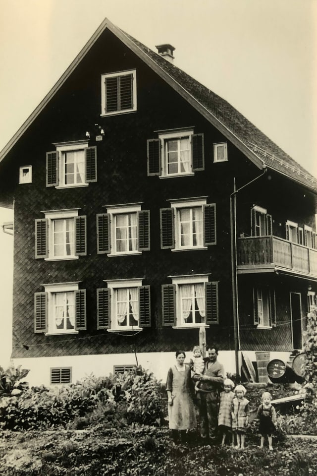 Dreistöckiges Bauernhaus. Davon Bauernfamilie. Dreistöckiges Bauernhaus. Davon Bauernfamilie.
