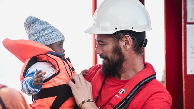 Ein gerettetes Kind und ein Helfer auf dem Rettungsschiff Vos Hestia. Ein gerettetes Kind und ein Helfer auf dem Rettungsschiff Vos Hestia.