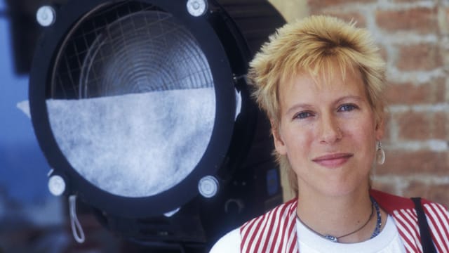 Eine junge Frau mit kurzen Haaren steht vor einem Scheinwerfer. Eine junge Frau mit kurzen Haaren steht vor einem Scheinwerfer.