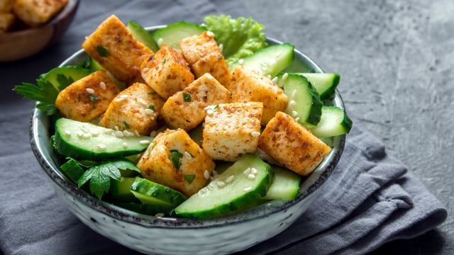 Ein Teller mit Tofu und Gurken Ein Teller mit Tofu und Gurken