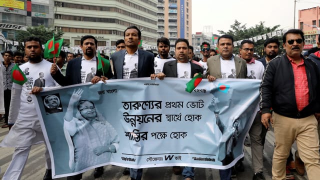 Bangladeschi mit einem Wahlplakat für die amtierende Premierministerin Bangladeschi mit einem Wahlplakat für die amtierende Premierministerin