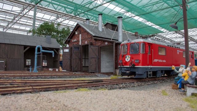 Gartenbahn, roter Zug mit Modellfiguren am Gleis Gartenbahn, roter Zug mit Modellfiguren am Gleis