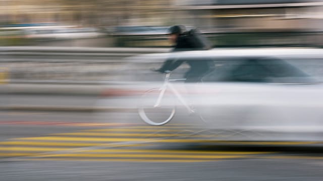 Fussgängerstreifen über den ein Auto und ein Velo flitzen (unscharf) Fussgängerstreifen über den ein Auto und ein Velo flitzen (unscharf)