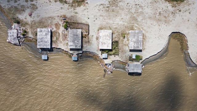 Luftaufnahme von Häusern, die an einer Küste stehen und gefährlich nahe am Wasser stehen. Luftaufnahme von Häusern, die an einer Küste stehen und gefährlich nahe am Wasser stehen.