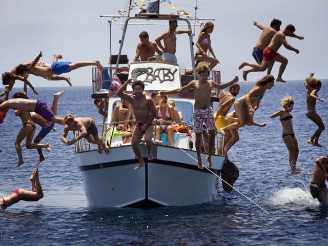 Junge Menschen springen von einem Boot ins Meer. Junge Menschen springen von einem Boot ins Meer.