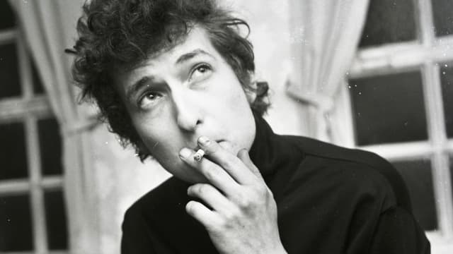 Bob Dylan in jungen Jahren hält eine Zigarette an den Mund.