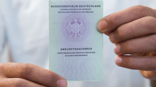 Zwei Hände halten einen Asyl-Ausweis Zwei Hände halten einen Asyl-Ausweis