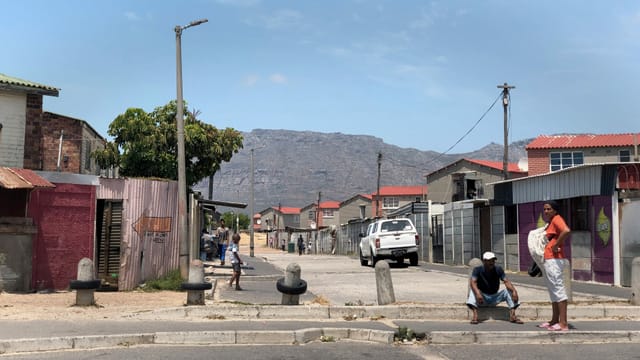 Mann und Frau auf Strasse, im Hintergrund sieht man den Tafelberg Mann und Frau auf Strasse, im Hintergrund sieht man den Tafelberg