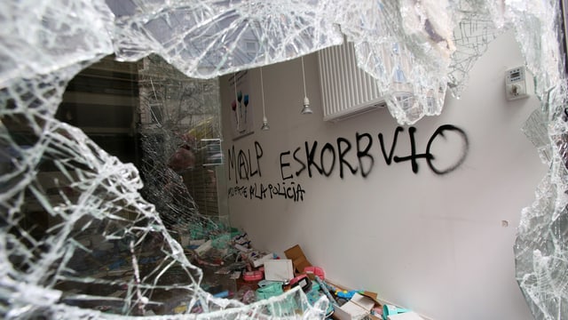 Blick durch eine eingeschlagene Fensterscheibe eines Geschäfts auf eine versprayte weisse Wand im Innern. Blick durch eine eingeschlagene Fensterscheibe eines Geschäfts auf eine versprayte weisse Wand im Innern.