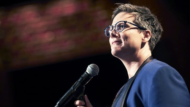 Hannah Gadsby auf der Bühne vor einem Mirkofon. Hannah Gadsby auf der Bühne vor einem Mirkofon.