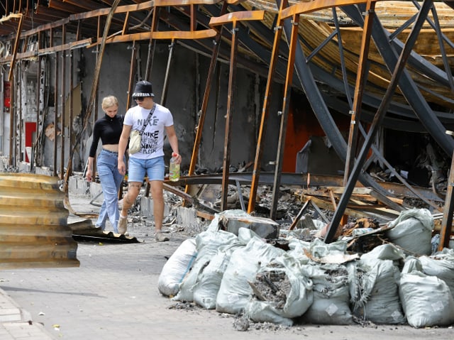 Ein Paar läuft an einem zerstörten Markt in Donezk vorbei.