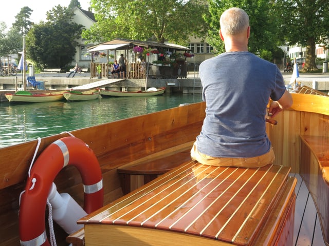 Mann steuert Motorboot auf Ufer zu Mann steuert Motorboot auf Ufer zu