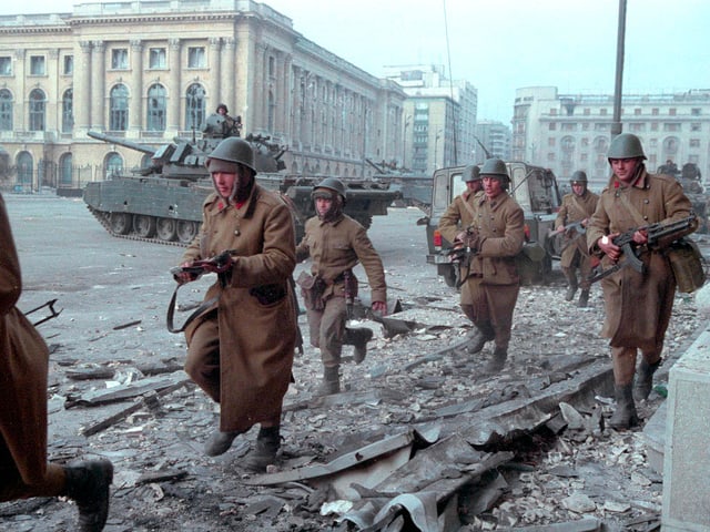 Rennende Soldaten, im Hintergrund stehen Panzer
