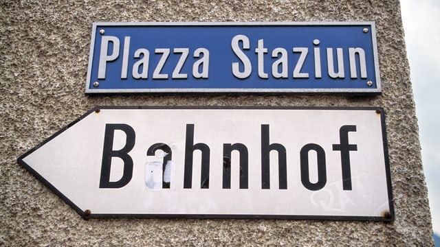 Schilder. Auf dem einen Steht Bahnhof, auf dem anderen Plazza Staziun. Schilder. Auf dem einen Steht Bahnhof, auf dem anderen Plazza Staziun.