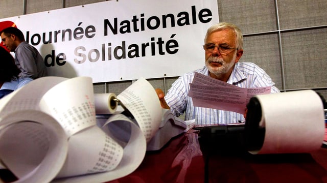 Eine Person rechnet die Gesamtsumme der Spenden aus. Eine Person rechnet die Gesamtsumme der Spenden aus.