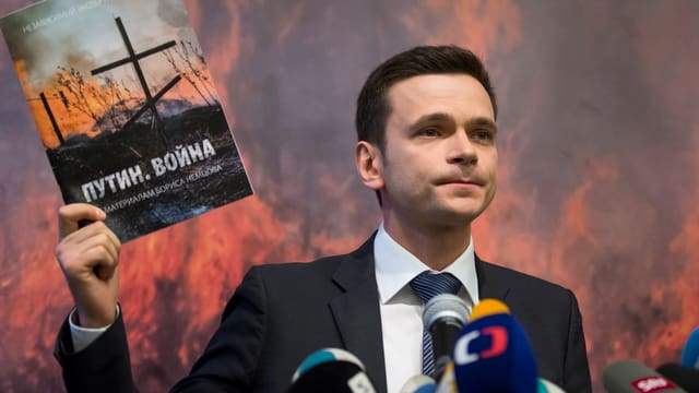 Ein Mann hält einen Bericht in die Luft. Ein Mann hält einen Bericht in die Luft.