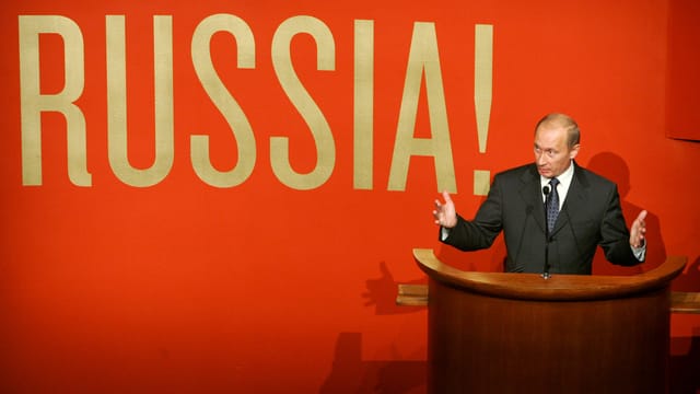 Wladimir Putin vor roter Wand mit der Aufschrift «Russia». Wladimir Putin vor roter Wand mit der Aufschrift «Russia».